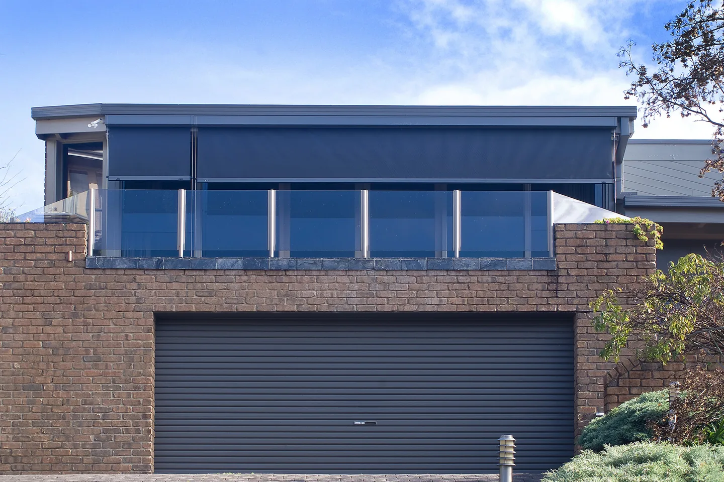 Upper-level balcony with wire guided blinds lowered behind the glass balustrade
