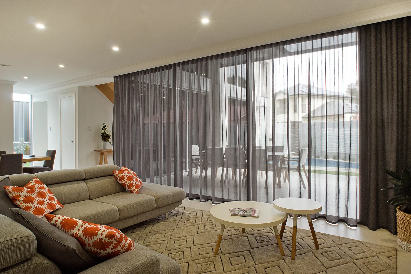Living room with charcoal S-fold sheer curtains drawn across a wall of sliding doors