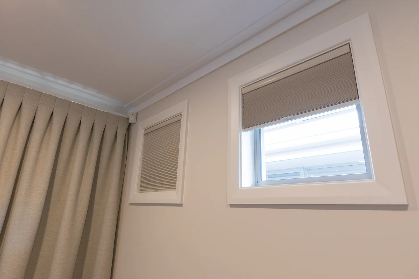 Pinch-pleat curtain on a concealed track beside high windows