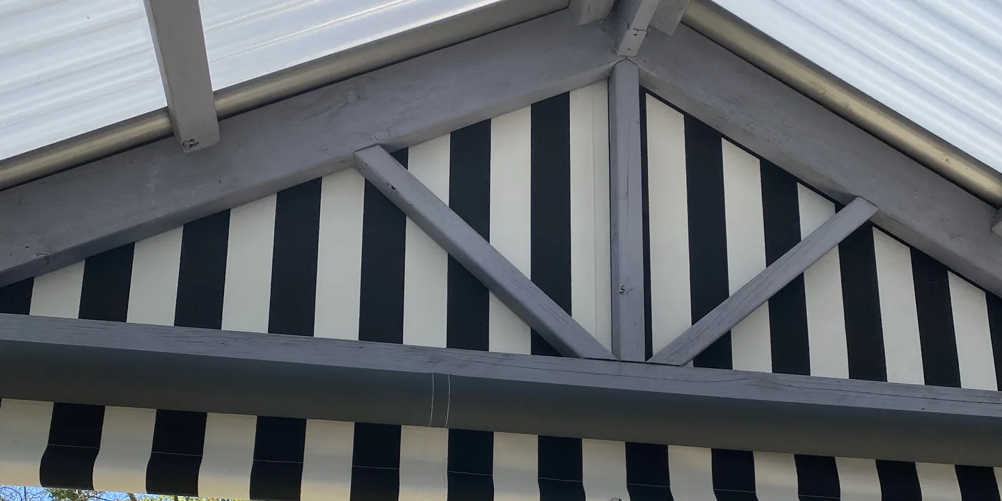 Black and white striped fabric infill panels fixed into the gable ends of a pergola