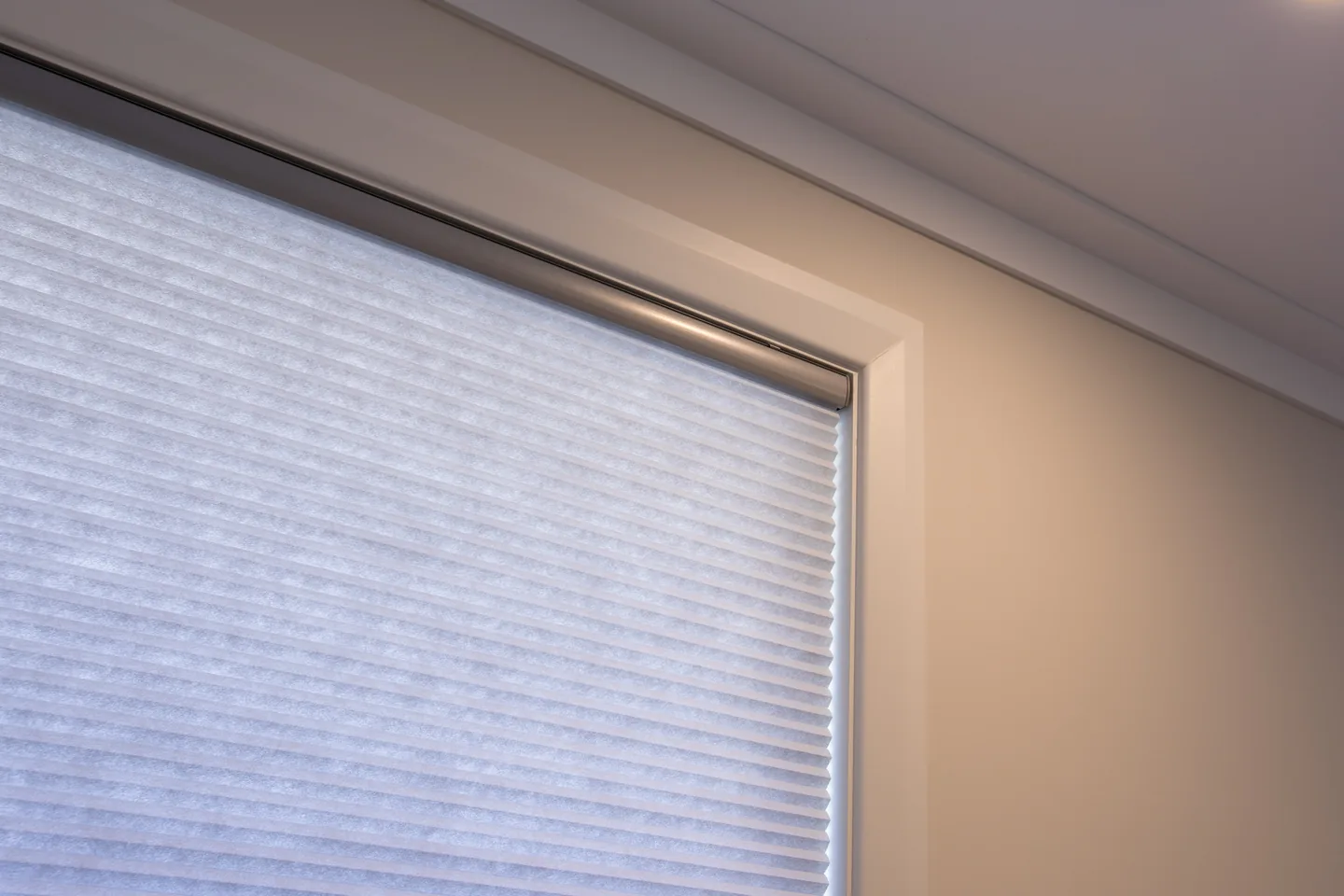 Close view of honeycomb blind fabric and its slim headrail in a window reveal