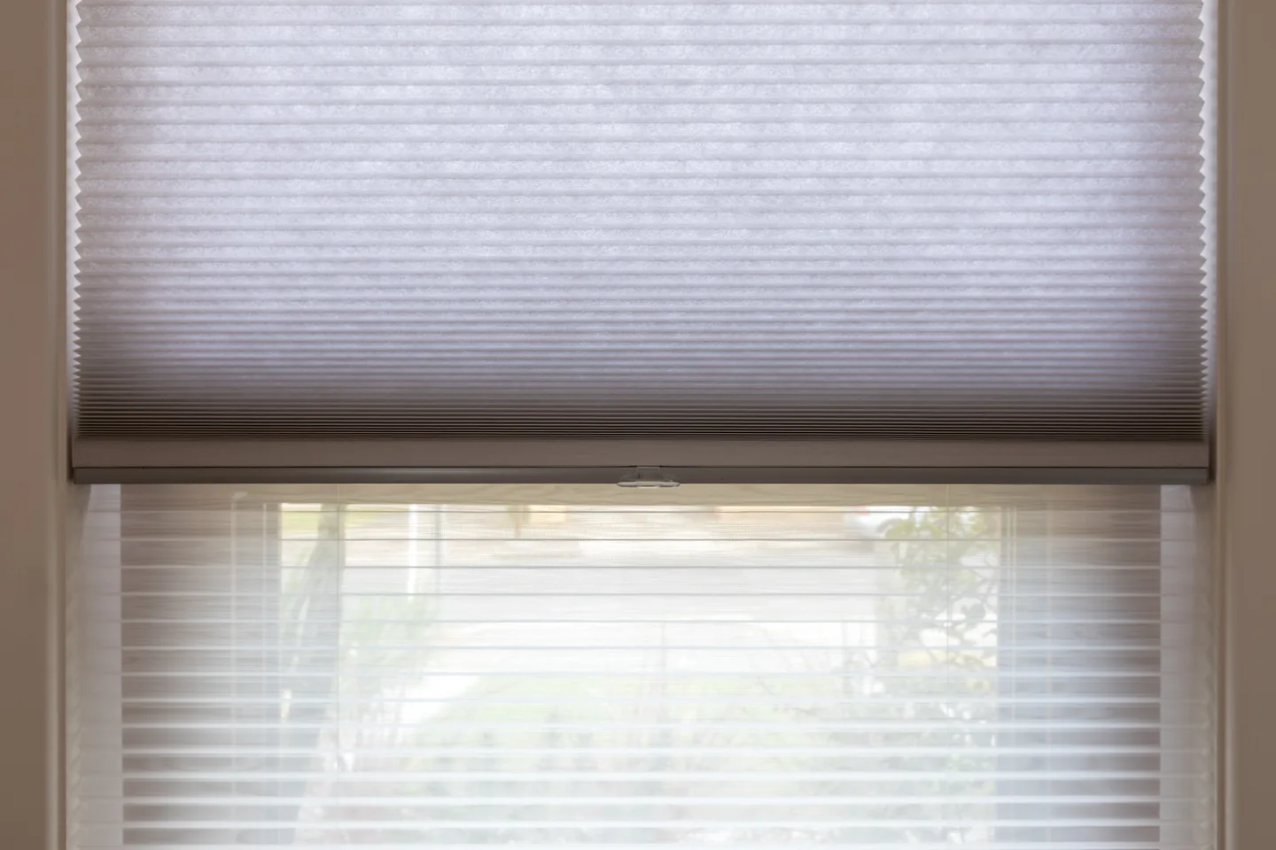 Honeycomb blind raised partway in a wide window