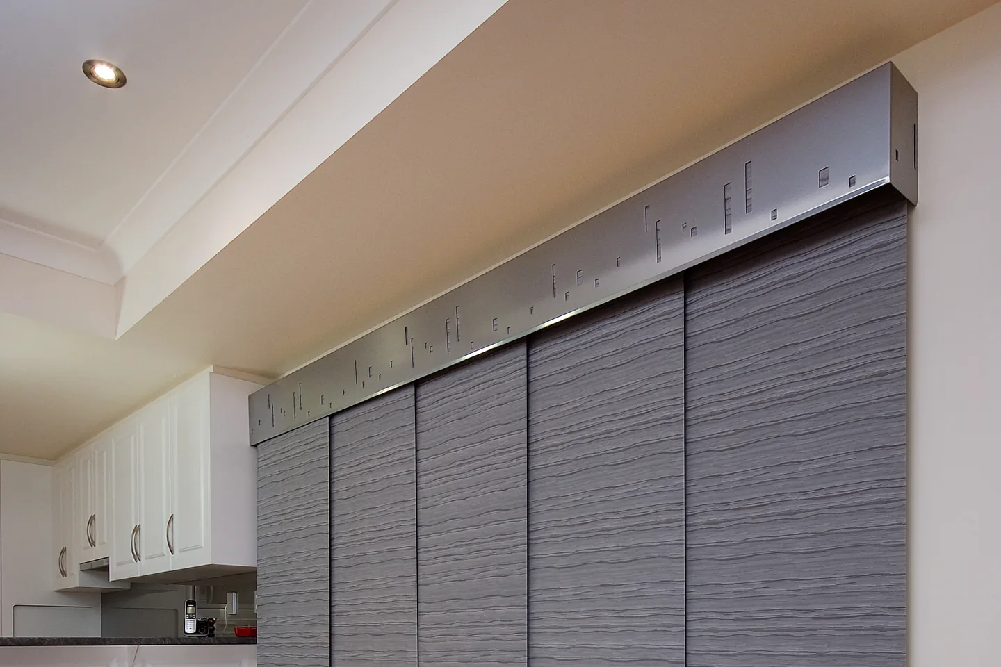 Tall grey fabric panels hanging from a track under a pelmet beside a kitchen