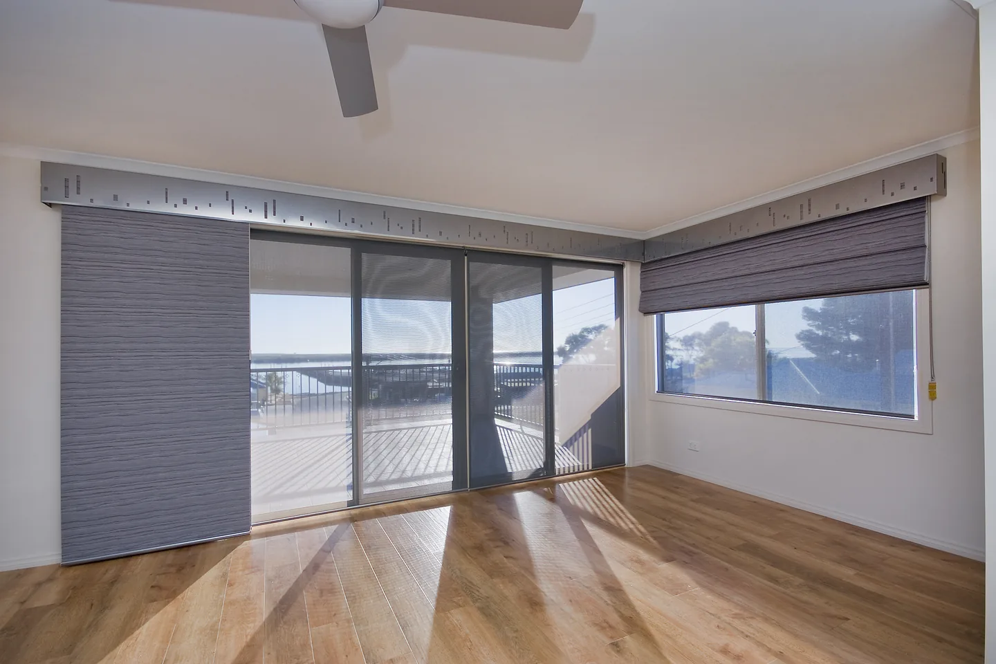Panel glide blind stacked to one side of a glass wall, with a matching blind on the corner window