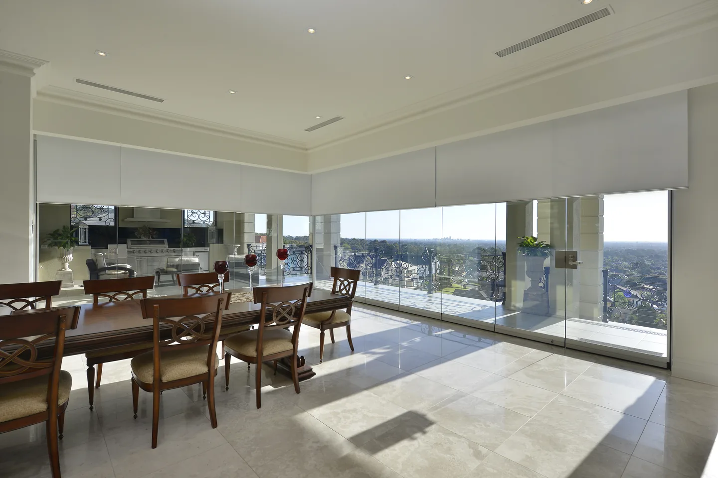 Open-plan dining room with roller blinds raised into a ceiling-line fascia above a long run of windows
