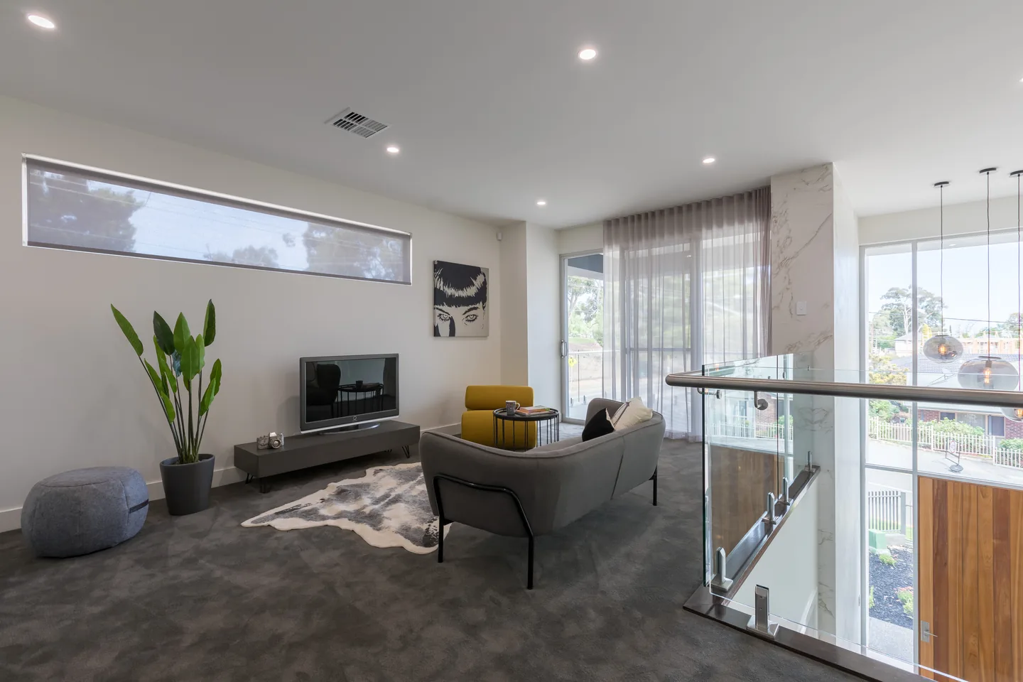 Upstairs living area with a sunscreen roller blind lowered over a long highlight window