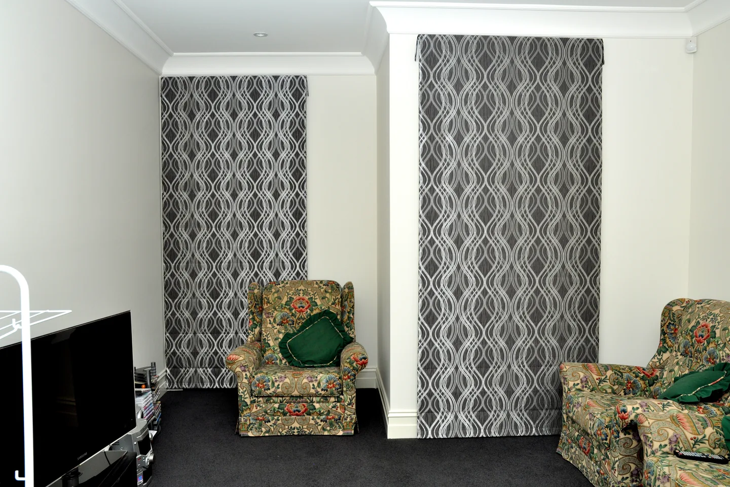 Two full-length Roman blinds in a grey wave pattern lowered over tall windows