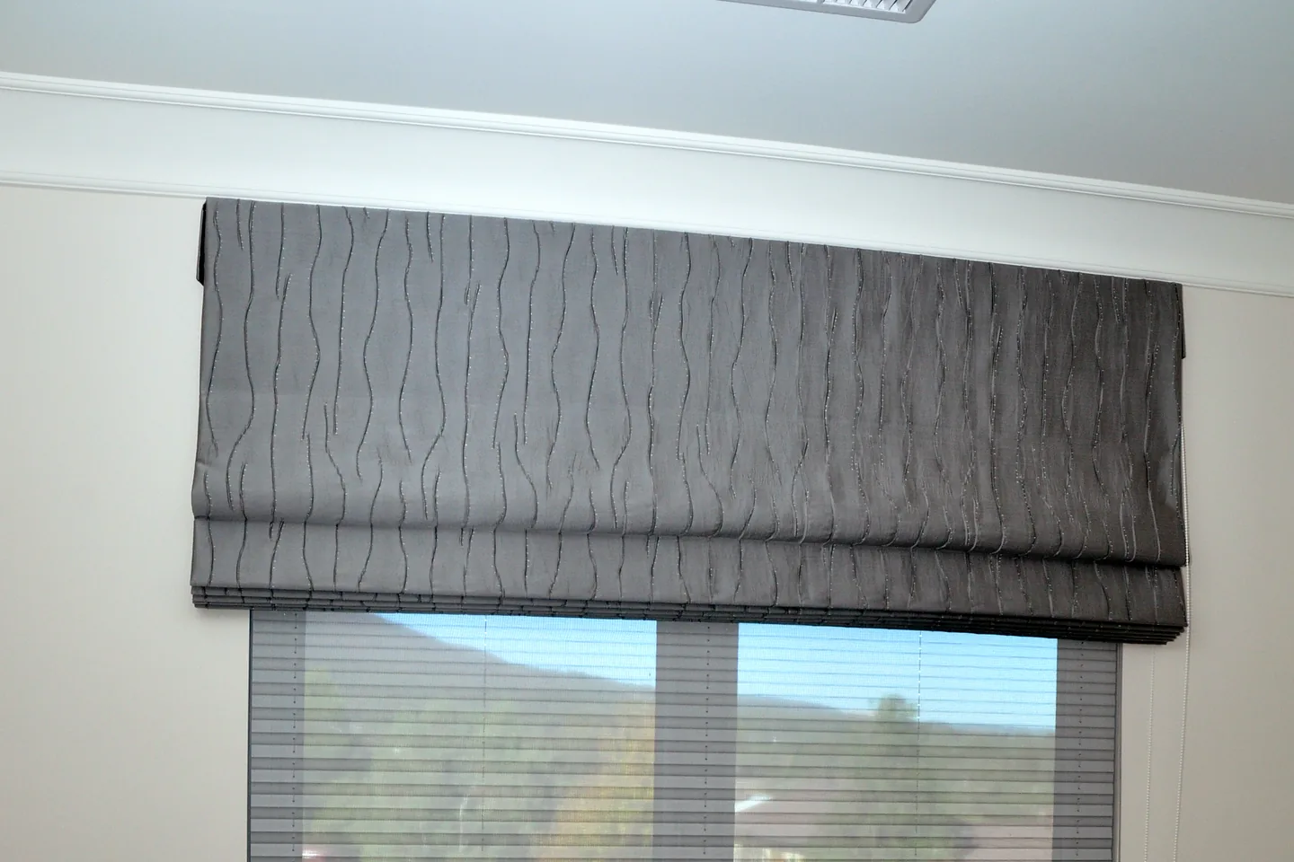 Charcoal Roman blind stacked in folds at the head of a sliding door