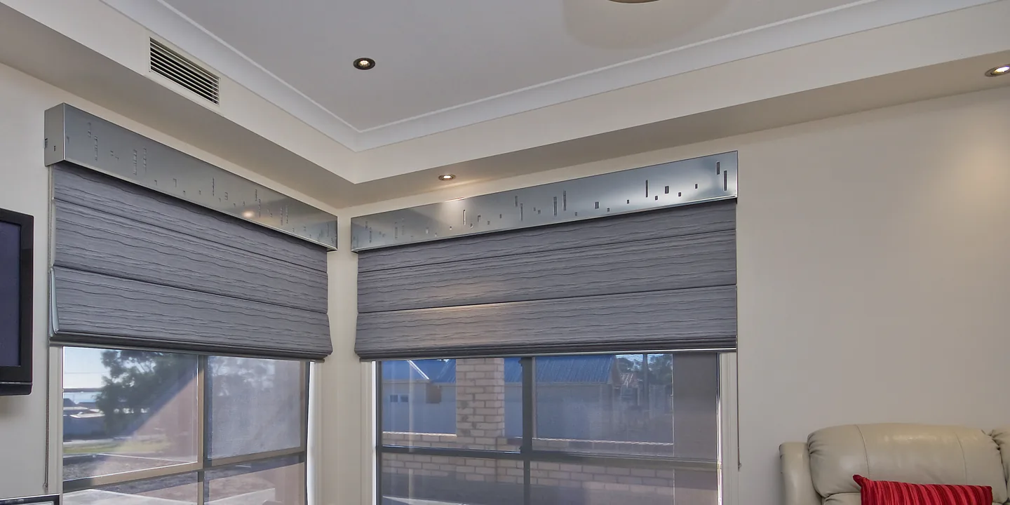 Corner living room with grey Roman blinds under decorative pelmets, raised part way over two windows