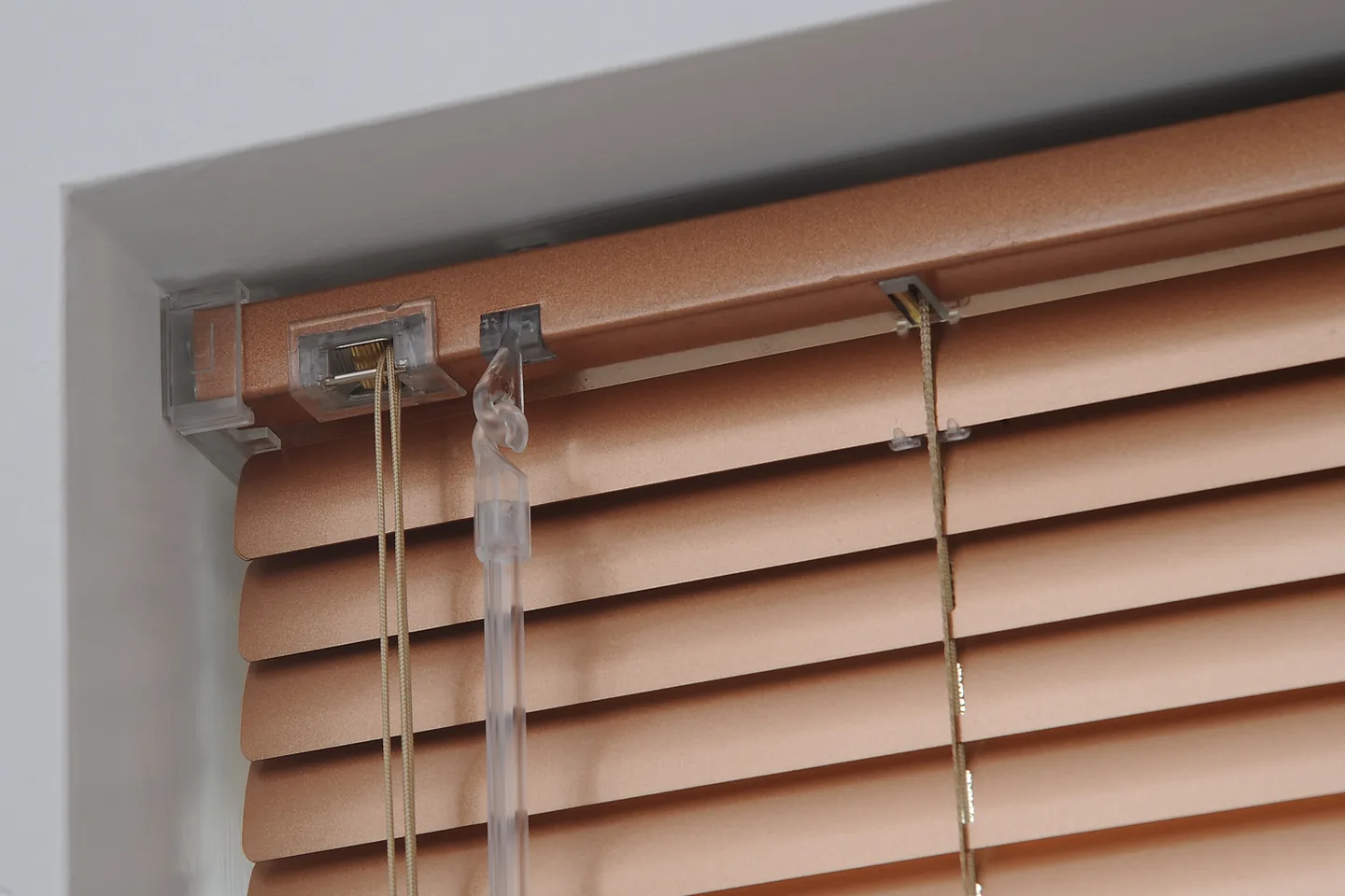 Close view of a timber-look aluminium Venetian headrail with its tilt and lift cords