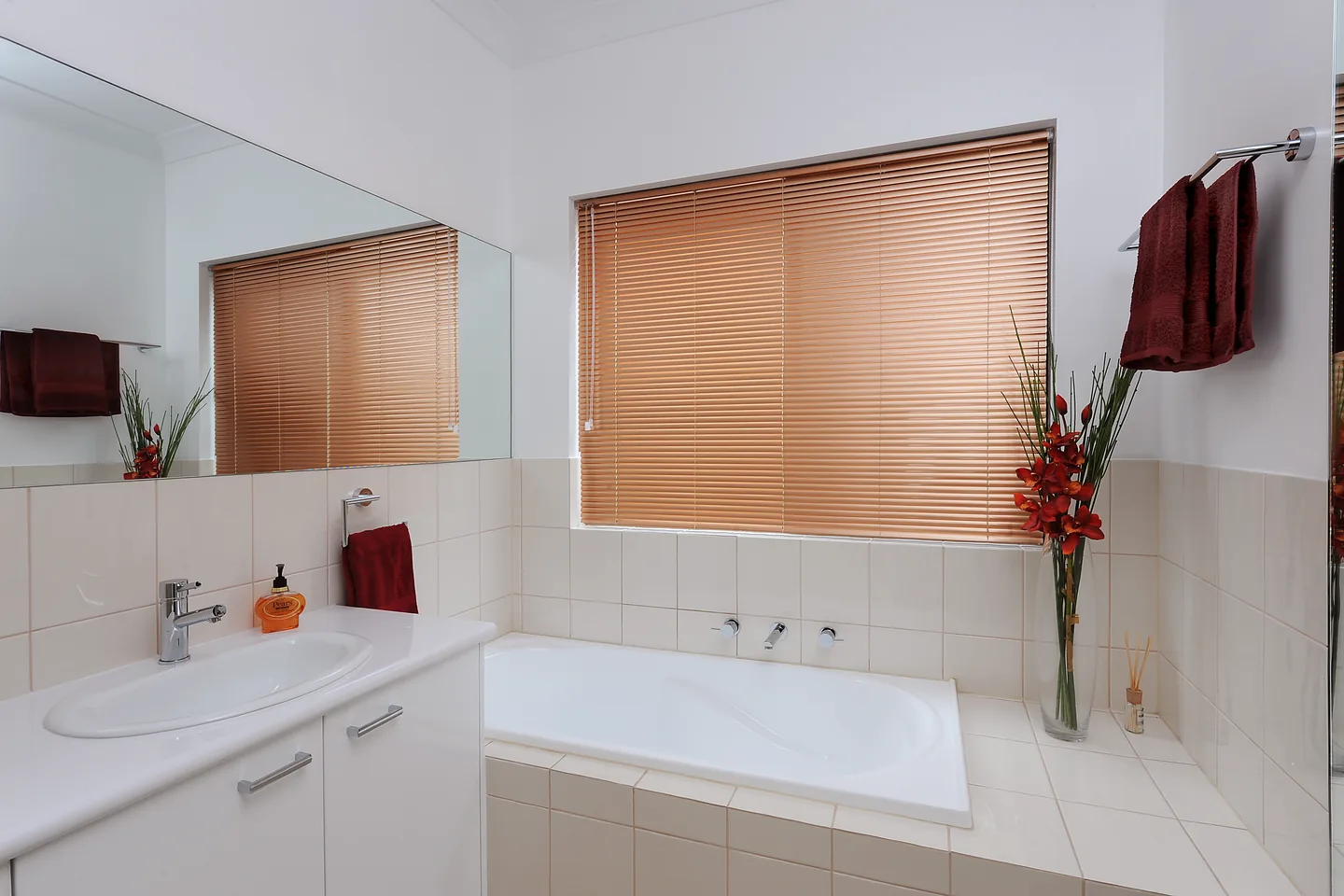 Bathroom with a timber-look aluminium Venetian blind over the window above the bath
