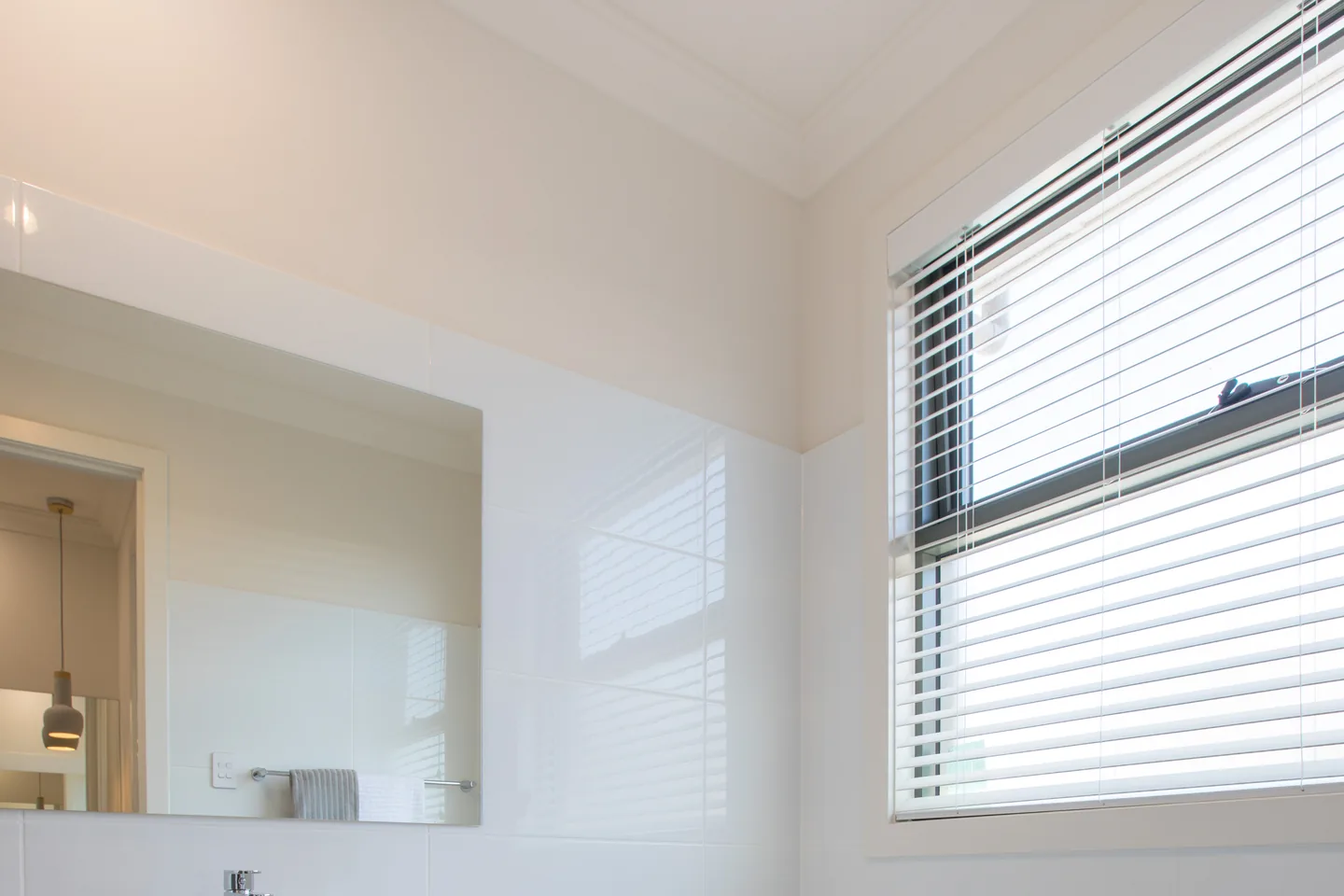 Bathroom window with a white Venetian blind above a vanity and bath
