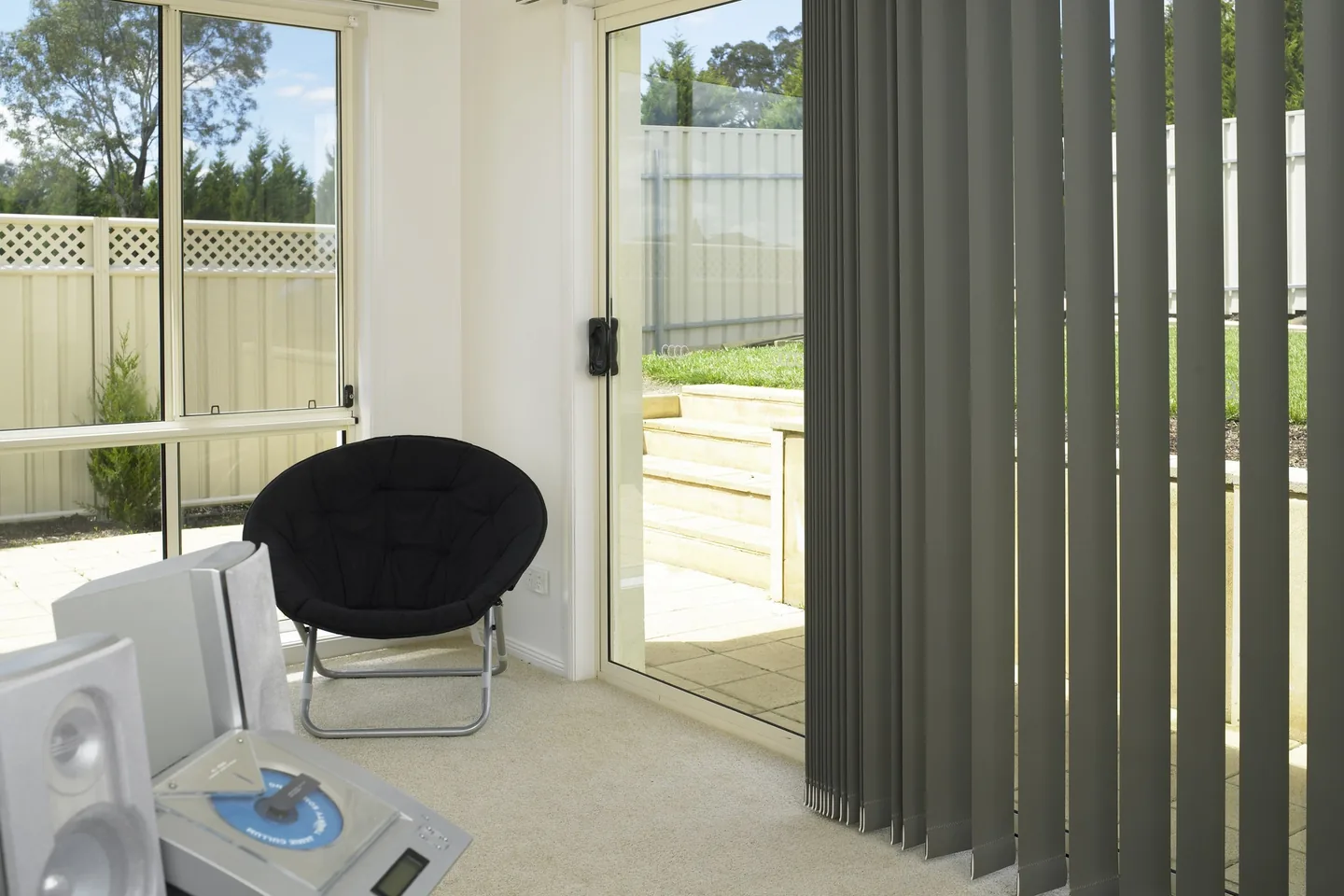 Grey vertical blind drawn back and stacked to one side of a sliding door