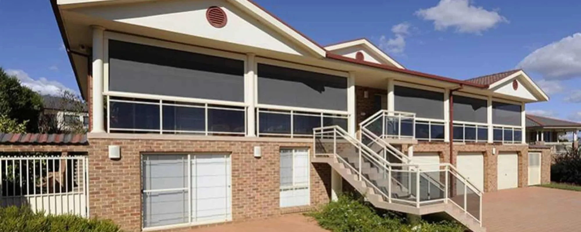 Wire guided straight drop awnings on the balconies of a brick home