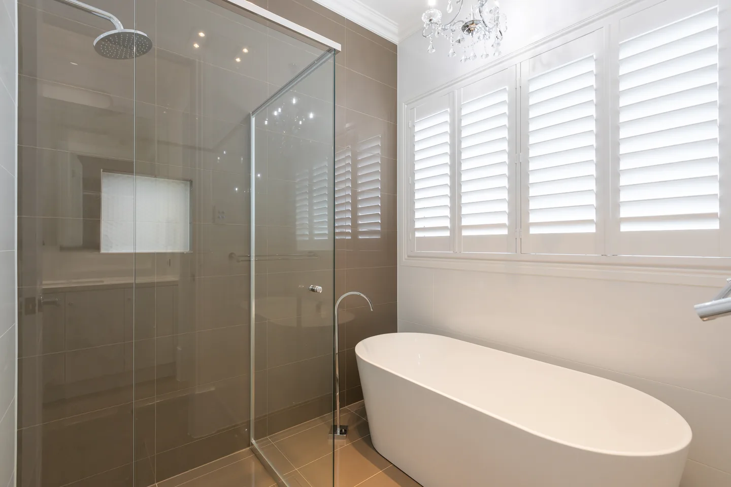 Bathroom with white plantation shutters above a freestanding bath