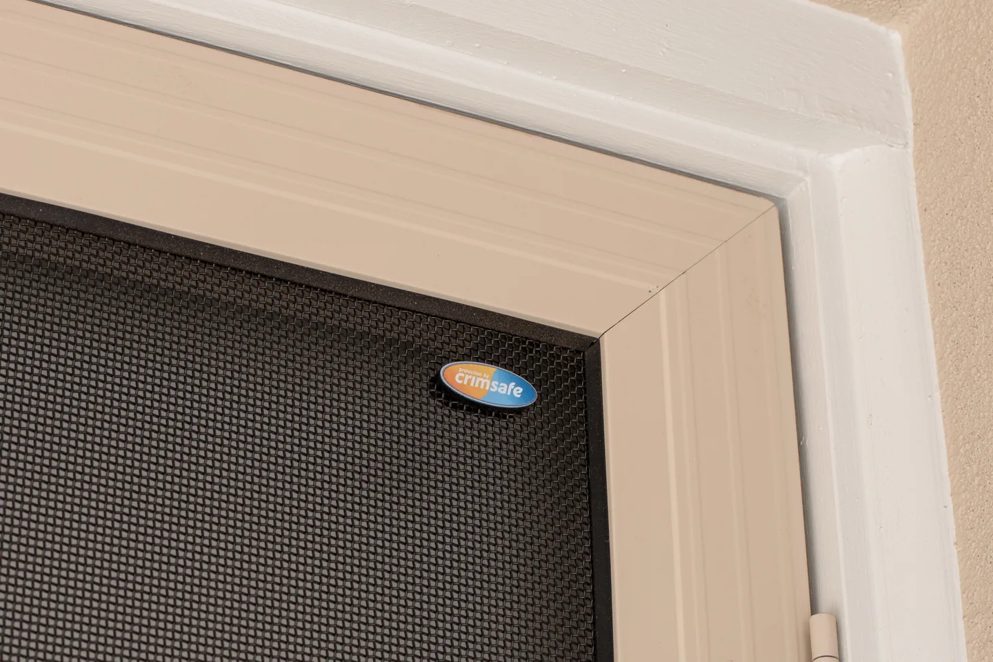 Top corner of a Crimsafe door showing the woven stainless steel mesh, the frame and the Crimsafe badge