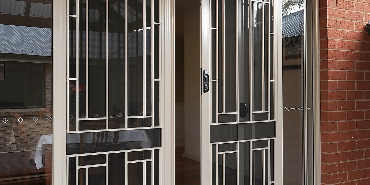 Pair of cream decorative aluminium security doors across sliding doors onto a timber deck