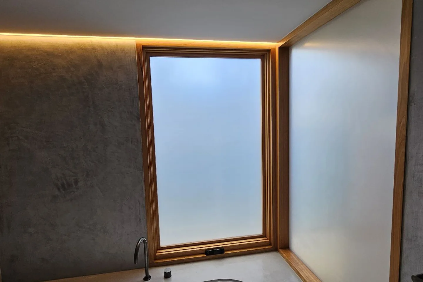 Bathroom with frosted film on a timber-framed window and the glass panel beside the bath