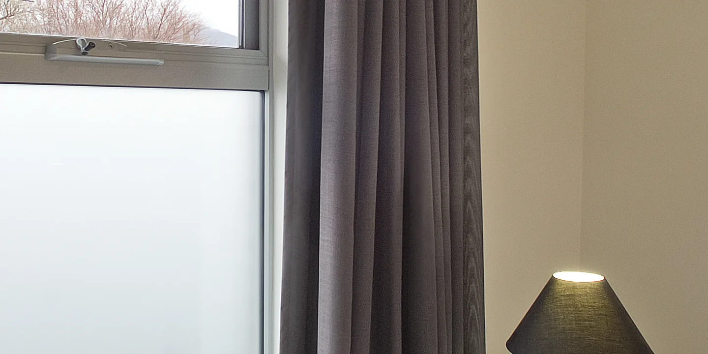 Bedroom window with frosted film on the lower glass and clear glass above, beside a charcoal curtain