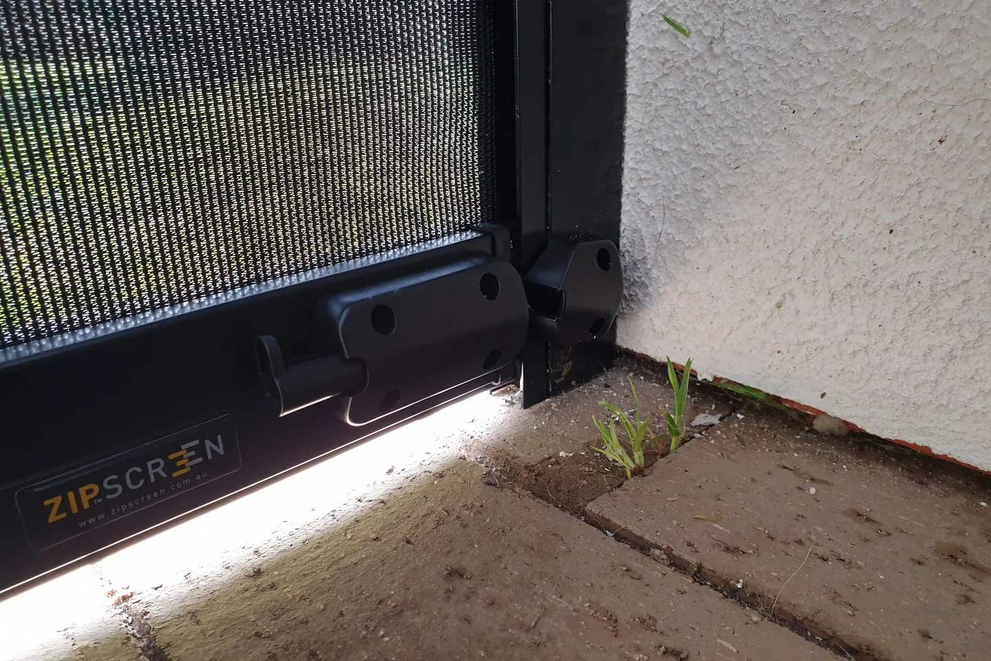 Close view of a Zipscreen bottom bar meeting its side channel at paving level