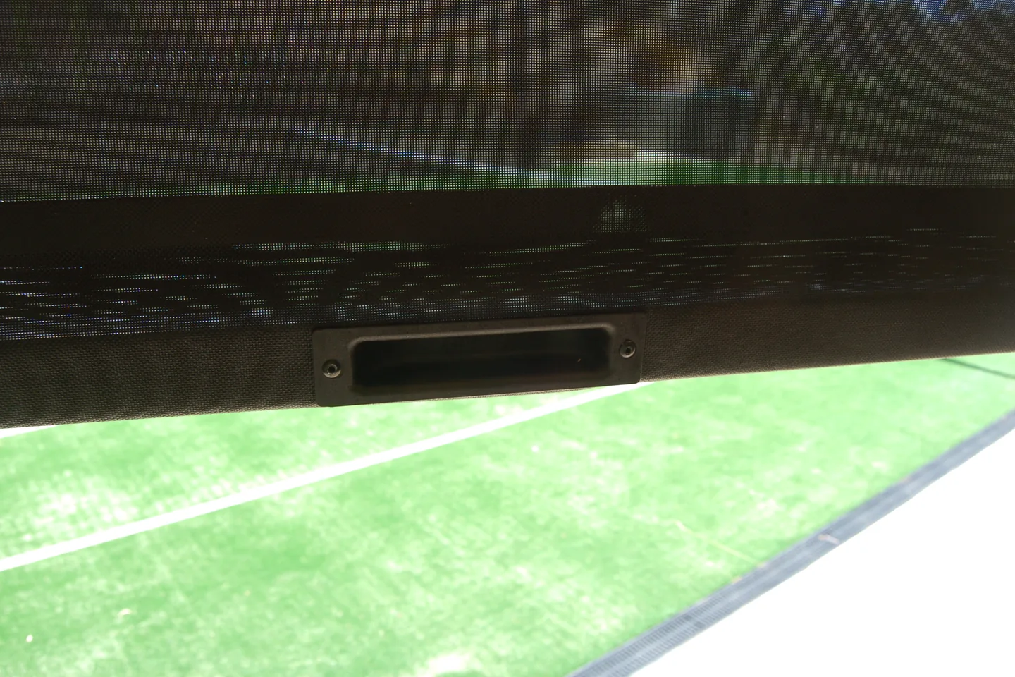 Recessed centre handle in the bottom bar of a lowered dark mesh Ziptrak blind