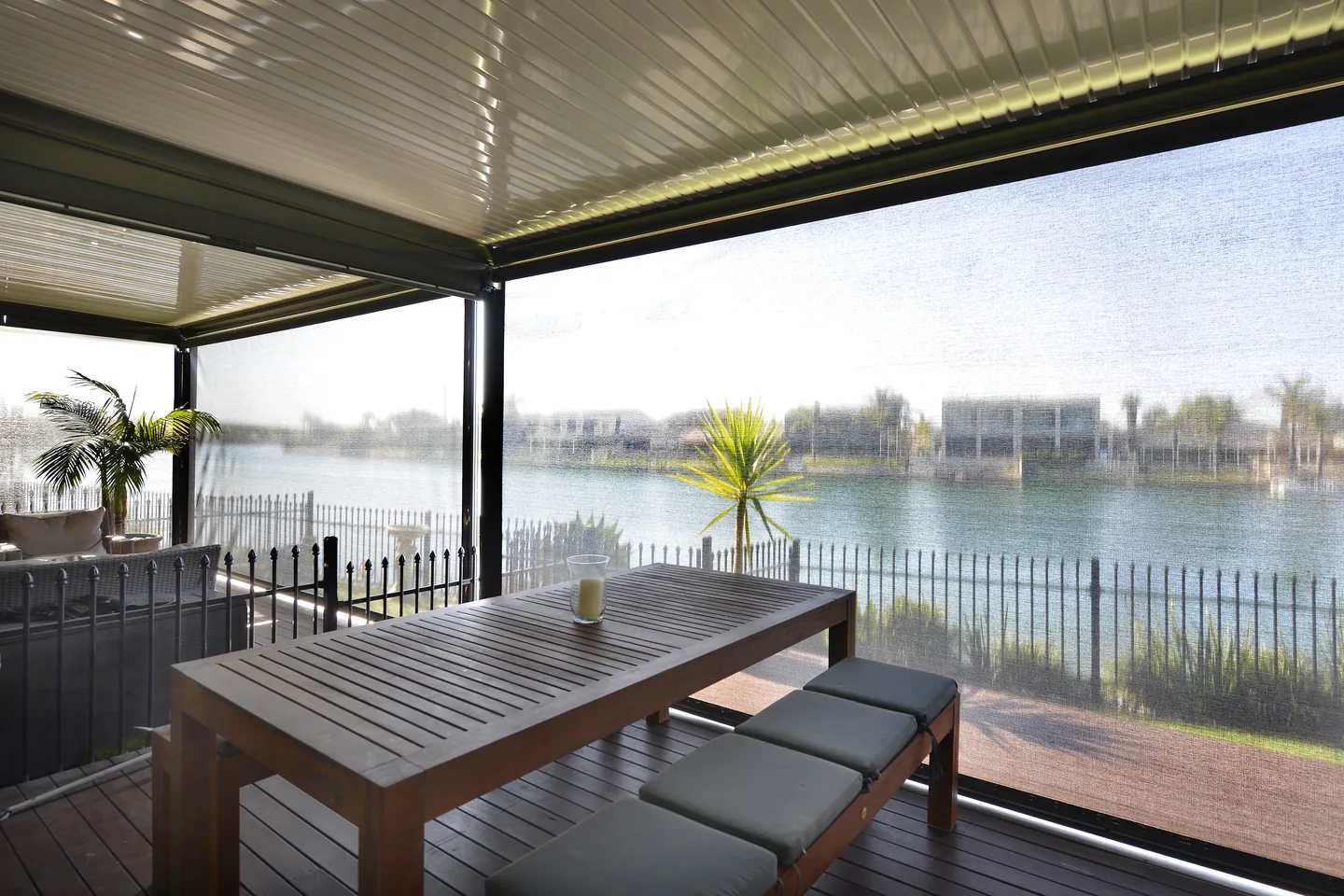 View from a covered deck through a lowered mesh outdoor blind towards the water
